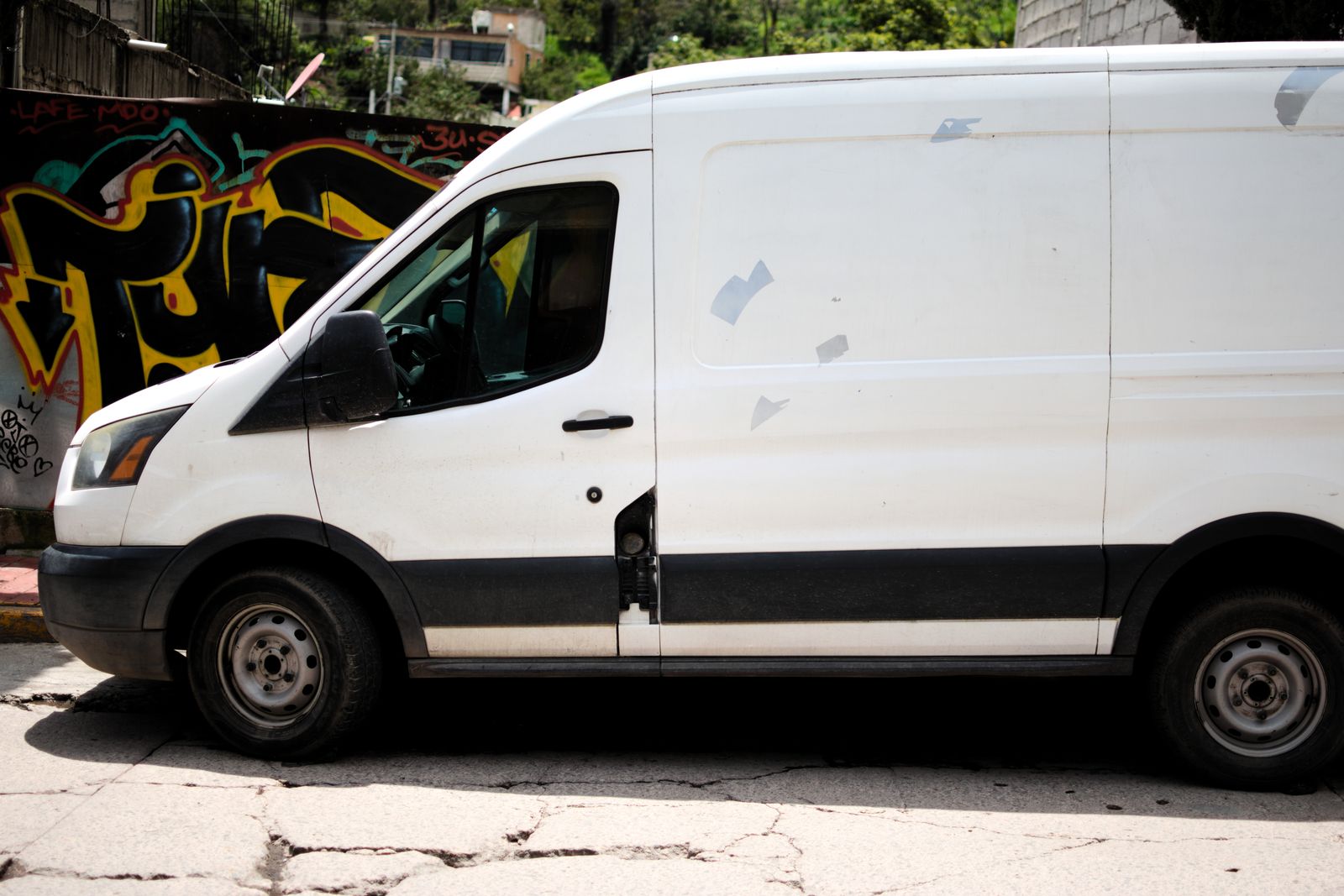 White cargo van parked beside a mural