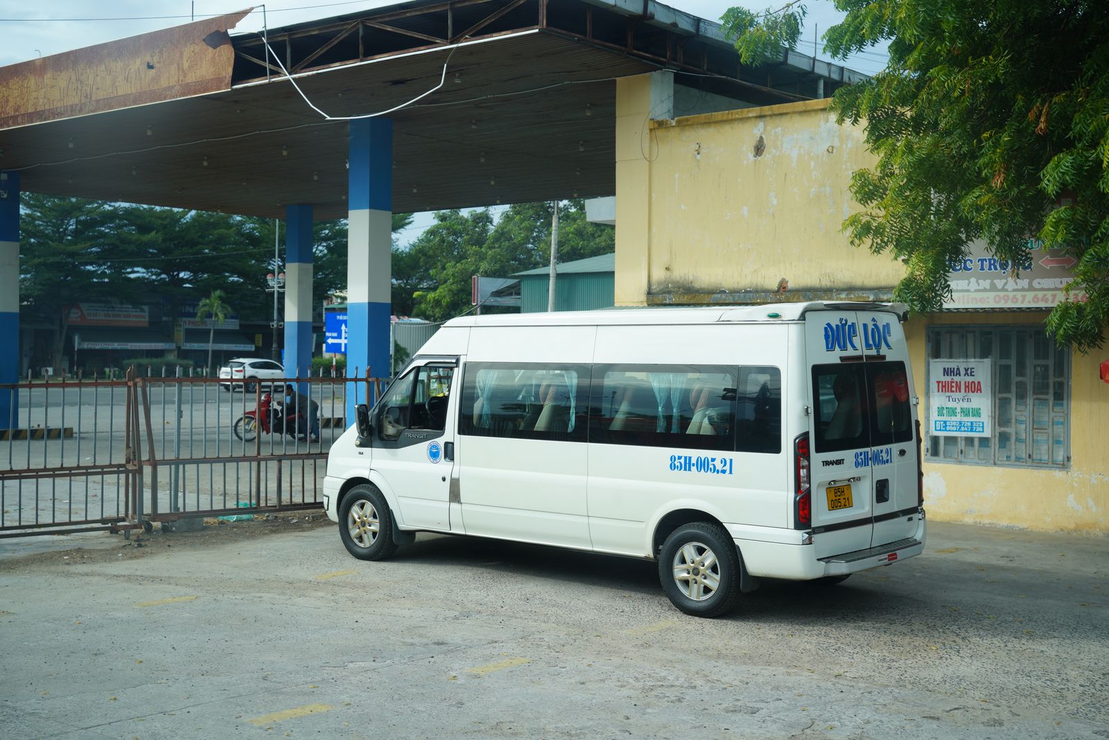 White passenger minibus under a station canopy