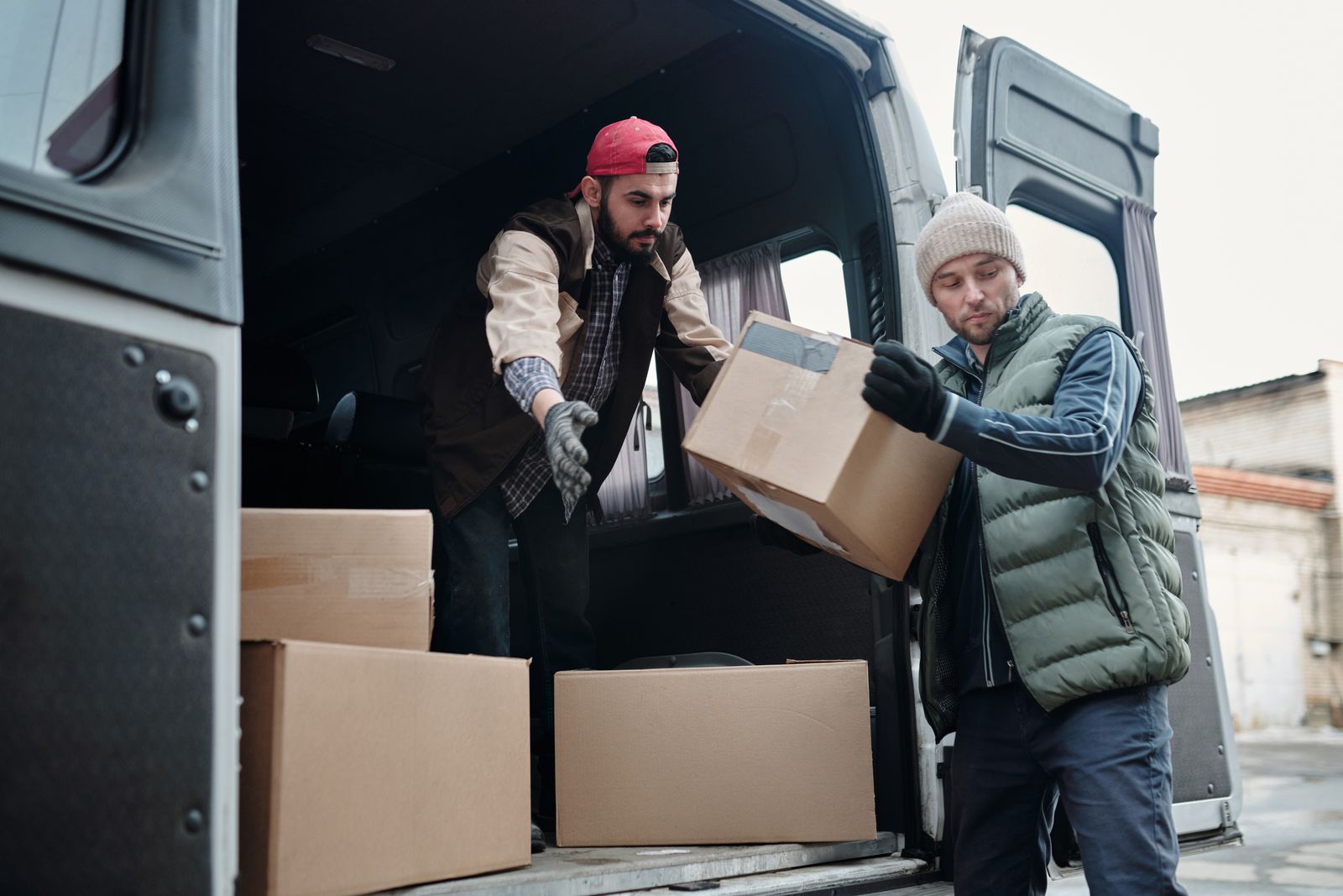 Two workers unloading boxes from a delivery van